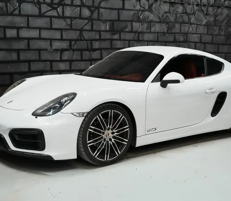 White Porsche Cayman GTS side profile showing the front wheel