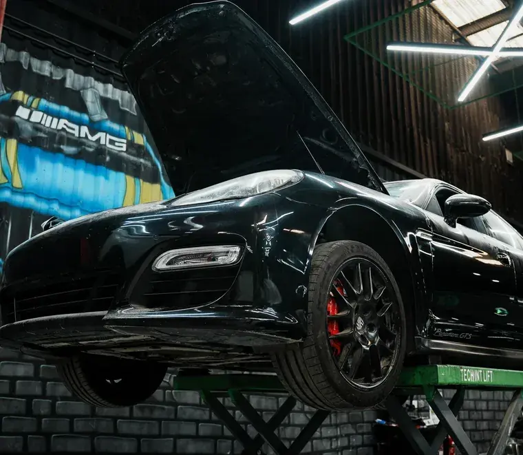 Black Porsche Panamera GTS raised on a two-post lift for transmission work