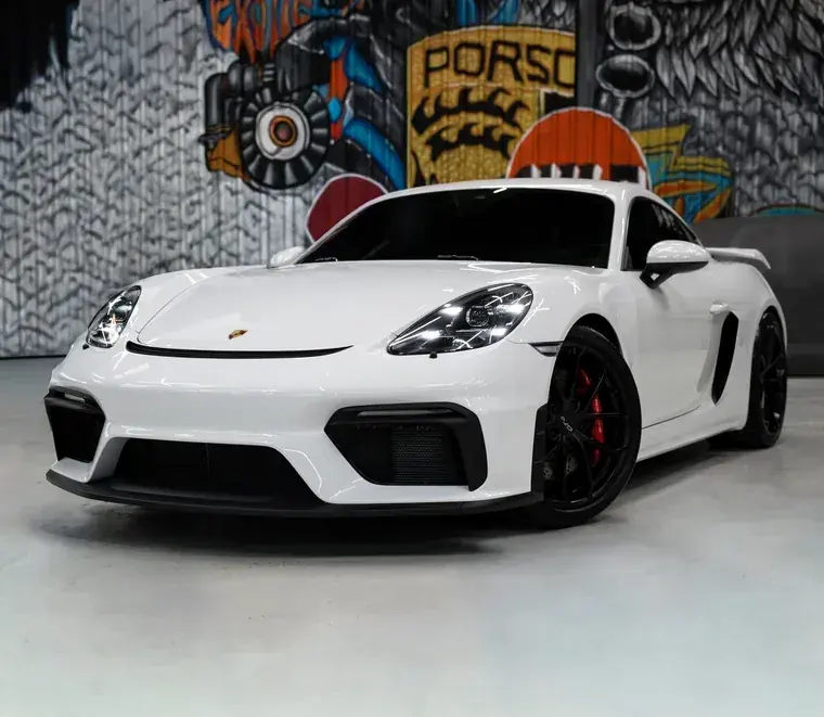 White Porsche 718 Cayman GT4 at the Exotic Auto Services workshop, marked with the 13 Porsche services